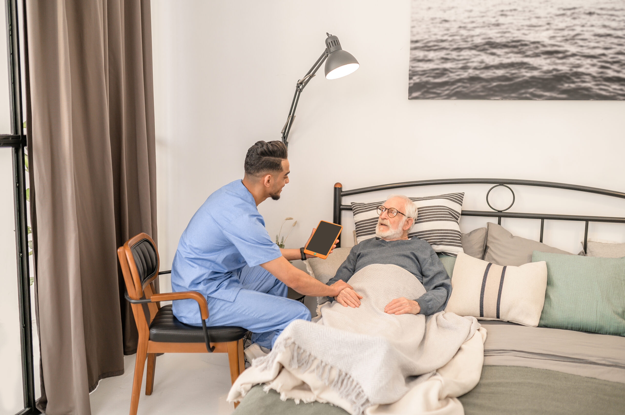 Qualified medical practitioner examining a sick elderly patient lying in bed during his home visit